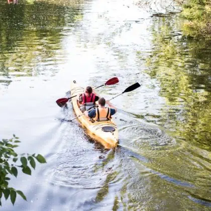 Two tourists kayakers woman and man touring canoeing in a lake on a summer day.Couple kayaking together in river.Back view.Summer family travel vacation concept. Active rest, water sports recreation.