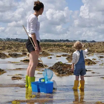 Une mère et sa fille cherchent de petits crabes à marrée basse